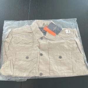 Beige overshirt från Morris - Säljer en fet Morris overshirt i beige i storlek M. Overshirten är helt oöppnad och är i perfekt skick. Hör av dig vid funderingar 
