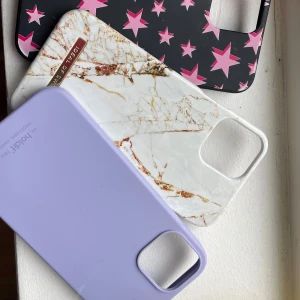 iPhone skal (3-pack) - olika mönster - Snygga iPhone-skal i tre olika designer: lila, marmormönster och svart med rosa stjärnor. Passar större iPhone-modeller med fyrkantig kameramodul. Skalen är i gott skick med minimalt slitage, perfekta för att skydda och ge din mobil en personlig stil. För IPhone 12, pris kan diskuteras 