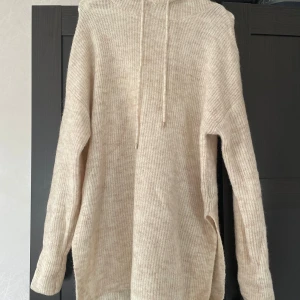 Off-white H&M hoodie - Säljer en mysig off-white stickad hoodie från H&M med huva och snörning. Hoodien har en loose passform och en ribbad struktur, perfekt för hösten! Materialet är dock lite kliande, därför rekommenderar jag att den bärs över någonting annat.