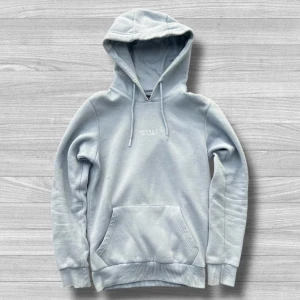 Ljusgrå hoodie från McKenzie XS - Snygg ljusgrå hoodie från McKenzie med broderad logga på bröstet. Klassisk känguruficka, snörning i huvan och mjukt material i bomullsblandning. Perfekt för chill dagar eller när du vill ha en clean streetstyle-look.