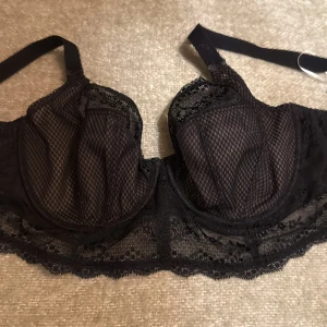 Svart bh  med meshdetaljer, Elomo, 85F - Säljer en svart bh  med snygga meshpaneler och spetsdetaljer. Den har justerbara axelband och hakknäppning bak. Perfekt för dig som gillar en edgy och feminin stil. Materialet är lätt och andas, med fina spetsmönster längs kanterna.