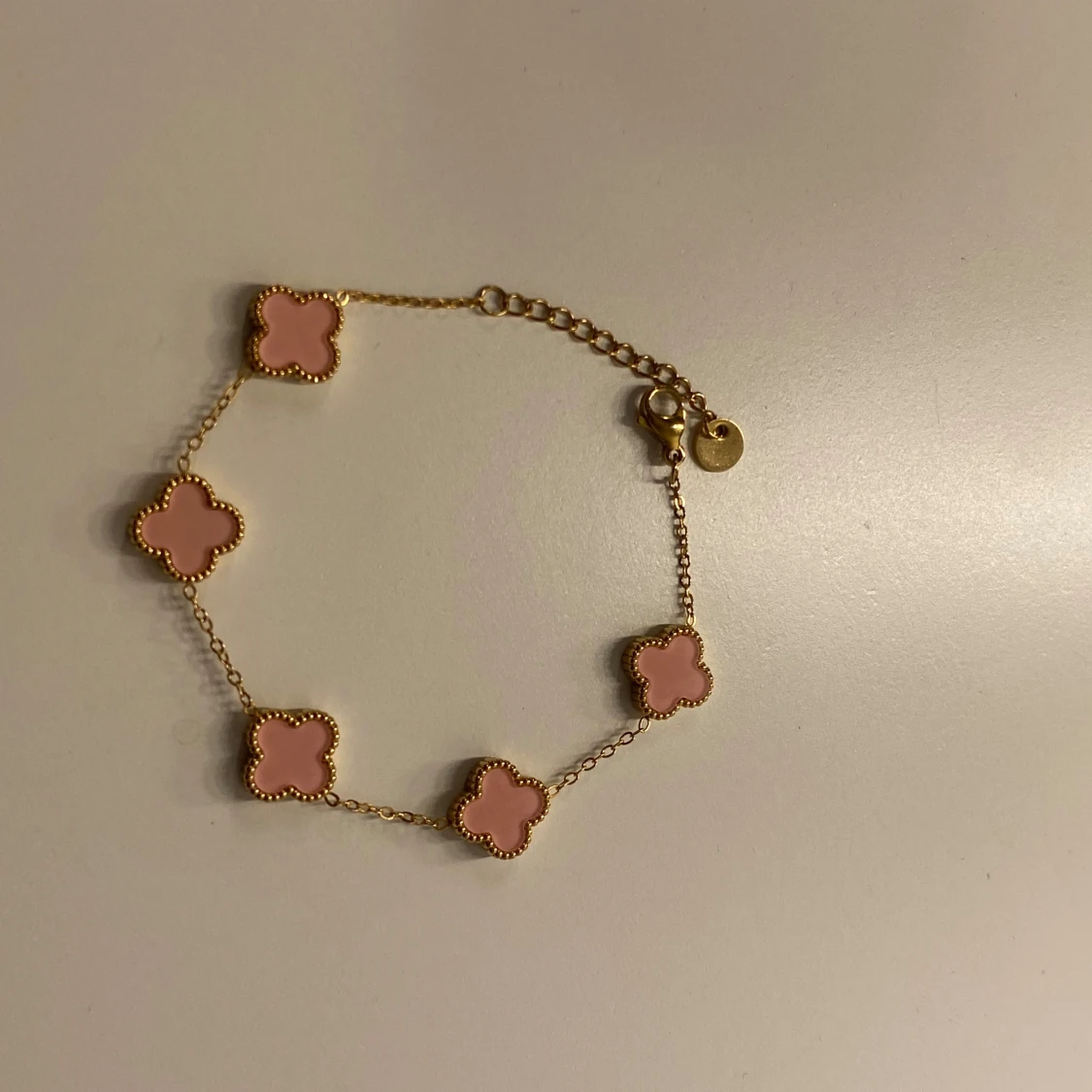 Guldfärgat armband med rosa klöver