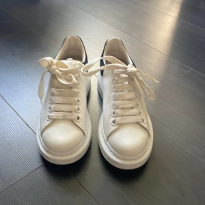 Vita sneakers med svart detalj - Snygga vita sneakers med chunky sula och svart detalj på hälen. Klassisk rund tå, breda vita skosnören och diskreta hål på sidorna för ventilation. Perfekta för en clean och modern look.