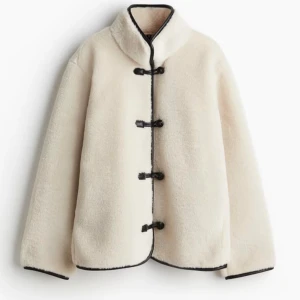 Vit teddyjacka med svarta detaljer - Säljer en vit teddyjacka med svarta spännen. Från H&M i storlek S, endast använd ett par ggr! Suuuperfin och mysig till hösten!🤎🤎pris kan diskuteras 