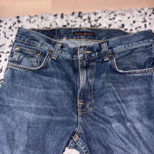  jeans från Nudie Jeans - Säljer ett par klassiska blå jeans från Nudie Jeans Co . W30,L30 är storleken och jeansen är i jätte bra skick förutom slitage längst nere på jeansen (baksida) (bild 5), utöver det snygga och i bra skick och personligen tycker jag slitage ger jeansen mer karaktär. Skriv vid minsta lilla fundering.