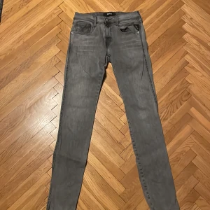 Replay Hyperflex Anbass grå jeans - Snygga Replay Hyperflex Anbass jeans i grå tvätt med smal passform. Klassisk femficksdesign, svarta detaljer och stretchigt material som sitter skönt. Perfekt för dig som gillar stilrena och moderna jeans med lite edge.