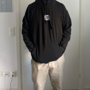 Svart hoodie från ODZ med tryck - Svart hoodie från ODZ med vitt tryck på bröstet. Tröjan har huva med snörning och en stor magficka framtill. Passformen är loose och materialet känns som mjuk bomull, perfekt för chill dagar. Snygg och enkel design som funkar till streetwear.