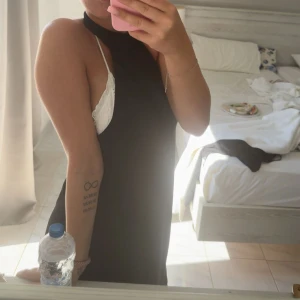 Svart halterneckklänning med öppen rygg - Säljer en svart halterneckklänning med öppen rygg och knapp i nacken. Klänningen är ärmlös och har en snygg, enkel design som ger en stilren look. Perfekt för varma dagar och sommarens alla tillfällen. Materialet känns lätt och följsamt🫶🏻