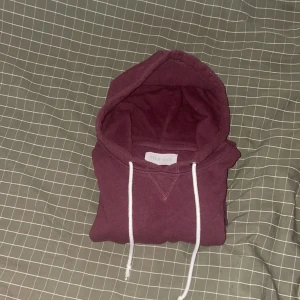 Vinröd hoodie från Pier One - Säljer en vinröd hoodie från Pier One med klassisk huva och vita snören. Tröjan är i mjuk bomull och har en enkel, stilren design som passar perfekt till jeans eller joggers. Perfekt för höst och vinter när du vill vara både bekväm och snygg. Storlek S, använd men noll defekter.