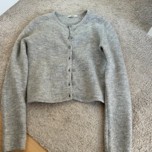 Grå stickad kofta.  - Mysig grå stickad kofta med knappar framtill från Gina. 