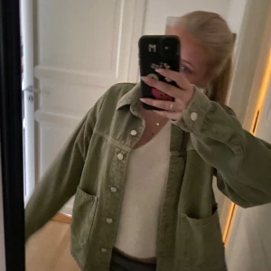 Grön jeansjacka från Zara - Säljer en oversized grön jeansjacka från Zara med stora fickor framtill och klassisk krage. Jackan har tryckknappar och är i ett mjukt bomullsmaterial. Perfekt att slänga över en hoodie eller t-shirt för en chill look.