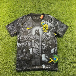 Svart Brasilien fotbollströja Nike M - Unik svart Brasilien fotbollströja från Nike med detaljerat tryck av Kristusstatyn och brasilianska symboler. Tröjan har korta ärmar, gul Nike-logga och Brasilien-emblem på bröstet. Tillverkad i Dri-FIT-material som andas och passar perfekt för träning eller match.