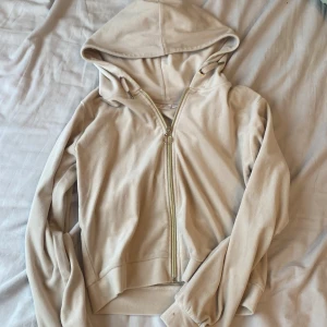 Beige kofta  från Gina Tricot - Beige kofta från Gina Tricot med dragkedja i guld och huva. Tröjan har snörning vid huvan och är långärmad. Katt finns i hemmet!