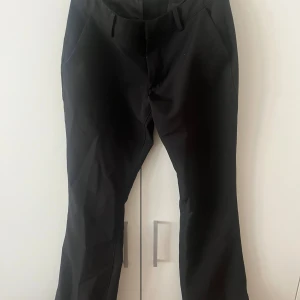 Svarta kostymbyxor från Bik Bok - Snygga svarta kostymbyxor från Bik Bok i storlek 36. Med slits. Perfekt för dig som gillar stilrena och enkla plagg.