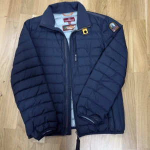 Mörkblå lättviktsdunjacka Parajumpers - Säljer min parajumper jacka eftersom jag växt ur den och inte använder den längre , Jackan är helt perfekt förutom att den har ett litet hål i den högra ärmen men de går att fixas . Ny pris 4.200 kr. Storlek Y-M vilket motsvarar cirka 164 cm