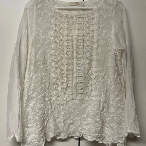 Vit broderad blus Odd Molly - Superfin vit blus från Odd Molly med broderade stjärnor och spetsdetaljer framtill och längs ärmarna. Långärmad modell i bomull med rund halsringning och vågig nederkant. I storlek 2 vilket motsvara storlek M