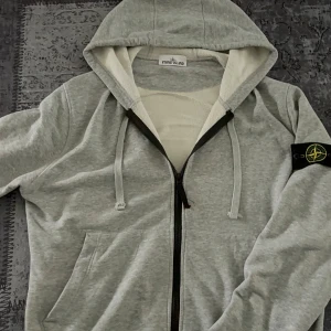 Stone Island zip-up hoodie  - Grå zip-up hoodie från Stone Island i storlek L. Kommer med tags som på bilderna. Helt ny & oanvänd. ✅ Fraktas samma dag Kan alltid diskuteras vid snabb affär 
