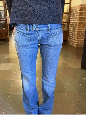 Blå dieseljeans - Säljer ett par blå bootcut jeans med stora, fyrkantiga fickor fram. Jeansen är från diesel och har dubbla knappar i midjan samt klassiska bakfickor. Materialet är jeanstyg och är en blå wash. Midjemått 38 cm, innerbenslängd 79 cm.