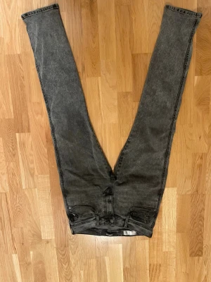 Replay jeans i mörkgrå tvätt, 32/32 - Säljer ett par Replay jeans i mörkgrå tvätt med klassisk femficksdesign och raka ben. Jeansen har snygga detaljer på bakfickorna och är tillverkade i slitstarkt bomullsmaterial. Perfekt för dig som gillar en stilren och enkel look.