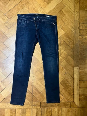 Mörkblå Replay jeansbyxor herr - Snygga mörkblå jeans från Replay med klassisk femficksdesign och raka ben. Byxorna har diskreta kontrastsömmar och en liten Replay-logga på fickan. Tillverkade i bomull med lite stretch för extra komfort.