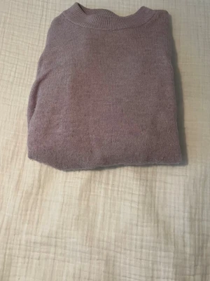 Ljuslila stickad tröja från H&M - Mysig ljuslila stickad tröja från H&M i storlek XS. Tröjan har rund hals, ribbade muddar vid ärmslut och nederkant samt långärmad passform. Perfekt för kyliga dagar och enkel att matcha med jeans eller kjol.