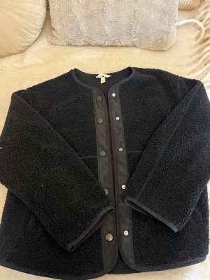 Svart teddyjacka från H&M - Mysig svart teddyjacka från H&M i storlek S. Jackan har rund hals, tryckknappar framtill och är gjord i fluffigt teddy-material.💖
