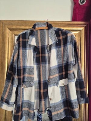 Rutig overshirt i blå och beige - Säljer en oversized rutig overshirt från Valerius Moments i blå, beige och grå toner. Jackan har långa ärmar, krage och två fickor med knapp framtill. Perfekt för lager-på-lager och chill stil.