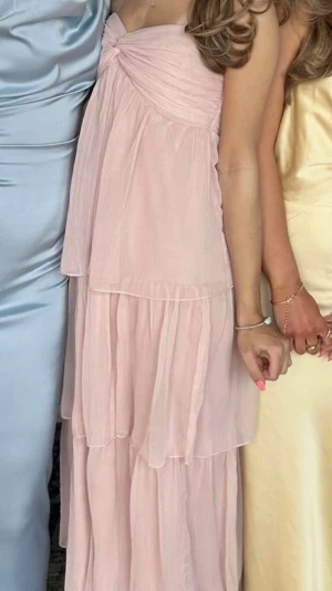 Ljusrosa balklänning - Säljer min superfina ljusrosa balklänning med volanger, den är från Nelly men verkar vara ute ur deras sortiment. Obs tryck på bilderna för att se dem större! Perfekt klänning till balen enligt min åsikt då färgen passar till allt och klänningen är sjukt snygg, ett band tillkommer även att knyta runt nacken men är valfritt. Den är bara använd en gång och ser helt ny ut. Pris kan diskuteras!❤️