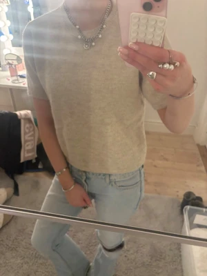 Beige stickad kortärmad topp - Säljer en beige stickad topp med korta ärmar och rund hals. Toppen har en enkel och clean design, perfekt att styla med jeans eller kjol. Materialet är mjukt och ger en chill vibe. Använd men i god skick! Hör av er vid funderingar 😊💕