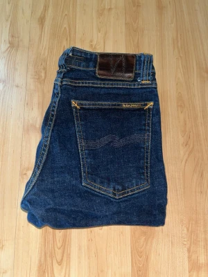 Nudie Jeans - Säljer ett par mörkblå skinny jeans från Nudie Jeans, skinny sam. Midja 30cm, längd 94cm. JAG SKICKAR EJ FLER BILDER NÄR JAG BÄR JEANSEN! för bättre inblick i passformen rekommenderar jag att googla på modellnamnet. För storleksguide kolla måtten noggrant då jeansen alltid kan vara uppsydda heller krympta och jag ej tar emot returer :) s5,4