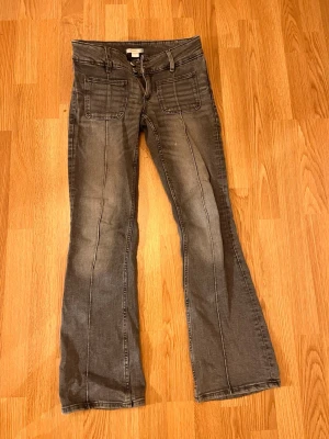 Grå bootcut jeans - Snygga grå jeans med bootcut-snitt och en lågmidjad design. Har defekt som syns på sista bilden