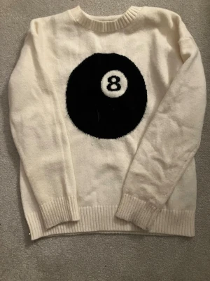 Vit stickad tröja med 8-ball print - Säljer en vit stickad tröja med ett stort svart 8-ball motiv på bröstet! Den är i storlek S! Bara använd några gånger! Den ser väldigt lång ut på bilden, men den sitter perfekt!