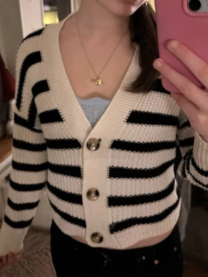 Randig kofta med knappar - Säljer en kofta med breda svarta och vita ränder. Koftan har stora dekorativa knappar framtill. Säljer då den aldrig kommer till användning. Den är i storlek xs. Använd gärna köp nu