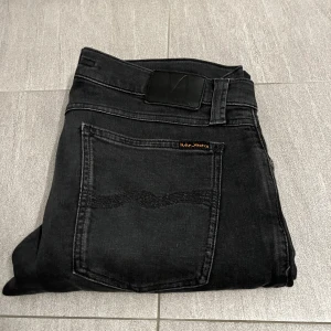 Svarta Nudie Jeans - Hej! Vi säljer nu dessa väldigt snygga nudie jeans | väldigt fint skick utan defekter. | sitter slim vilket är väldigt trendigt | modellen är ca 170cm och väger 59kg jeansen sitter lite stort så passar bäst om man är ca 175-178 cm lång | säljs nu för endast 349kr! | vid ytterligare funderingar hör av er!👍⭐️