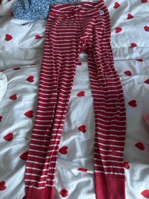 Randiga leggings från Polarn O. Pyret - Snygga röda och vita randiga leggings från Polarn O. Pyret, tillverkade i mjuk ekologisk bomull. De har en elastisk midja och smal passform, perfekta för chill dagar. Märkta med GOTS-certifiering för ekologiskt material.