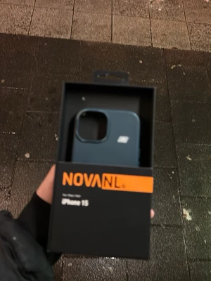 NOVANL iPhone 15 Skal - Skyddande mobilskal för iPhone 15 från NOVANL, levereras i originalförpackning. Skalets färg är blå och det ser ut att vara i nyskick utan synligt slitage eller defekter. Perfekt för att skydda din iPhone 15 mot repor och stötar.