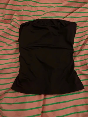  tubtopp - Säljer en mörklila tubtopp med elastisk kant upptill för att sitta på plats. Perfekt att matcha med jeans eller kjol och perfekt inför sommaren!! (Jag jämnförde tubtoppen med en svart tröja för att visa att den är mörklila för det syntes inte i kameran💜
