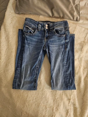 Snygga blå bootcut low-waist jeans från Gina Tricot, strl 152 - Jag säljer ett par snygga blå jeans från Gina Tricot med klassisk femficksdesign och dubbla silverfärgade knappar i midjan. Använda och därför i helt okej skick, därför priset. Bootcut och lågmidjade. Nypris runt 300 kr. Jag har själv sytt med svart tråd vid blixtlåset pga ett litet slitage som är ej så tydligt, se bilder. 💓💓