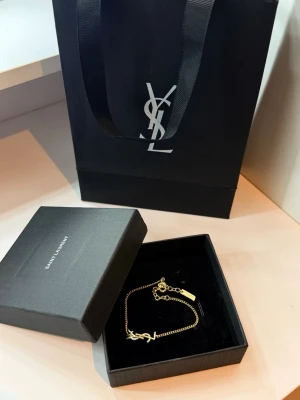 Ysl armband - ett armband från Saint Laurent i guld med YSL-logga jag fick den present och användade bara  två gånger men det ser ut väldigt ny👌Påse har en liten fläck i en av sidan.