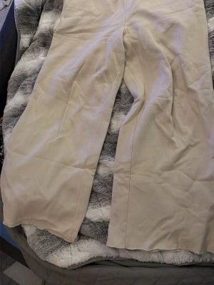 Beiga wide mjukisbyxor från H&M - Säljer ett par beiga mjukisbyxor från H&M i storlek M. Byxorna har bred och loose passform och resår i midjan för extra komfort. Materialet är mjukt och skönt, perfekt för chill dagar. Färgen är ljus beige och modellen är loose med raka ben.💗