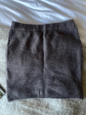 Mörkgrå stickad kjol från 157 - Säljer en mörkgrå stickad kortkjol från 157 i storlek XS. Kjolen har en enkel och rak passform med ribbad kant nedtill. Perfekt för dig som gillar mjuka och varma material under höst och vinter. Snygg att matcha med boots eller sneakers.