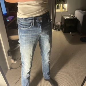 Slim fit jeans från Jack & Jones - Snygga blå jeans från Jack & Jones i modellen Slim/Glenn. Jeansen har en slim passform med klassisk femficksdesign och ljusa tvättade detaljer framtill. Perfekt för dig som gillar en modern och stilren look.