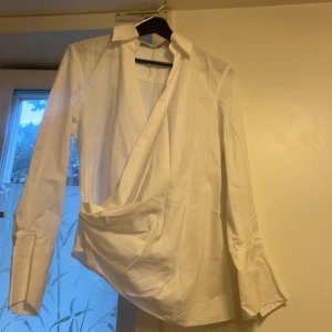Vit skjorta från Zara  - Vit skjorta med krage med slag och lång ärm som avslutas med manschett och guldfärgad knappar. Kan passa dig som har storlek M.