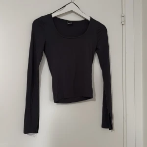 Mörkblåa långärmad topp från Gina Tricot - Säljer en svart långärmad topp från Gina Tricot i storlek XS. Toppen har en rundad, lite djupare halsringning och är figurnära i modellen. Materialet är mjukt och stretchigt, perfekt för en clean och enkel look. Passar dig som gillar minimalistisk stil.