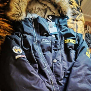 BERKELEY - Hartford Expedition Parka XL - Säljer en helt ny med prislapp Hartford Expedition Parka från designer företaget Berkeley i storlek XL. Butikspris 12.000-15.000kr. Jackan har snygga broderade patches, gula detaljer och en fet pälskantad huva. Stängs med både dragkedja och knappar. Perfekt för kalla dagar och riktigt stilren look.