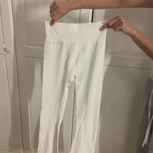 Vita ribbade leggings med medel midja - Snygga vita leggings med ribbad struktur och extra mid waist som ger en skön och smickrande passform. Stretchigt material som sitter tajt och följer kroppen. Perfekta att styla med en oversized hoodie eller crop top.