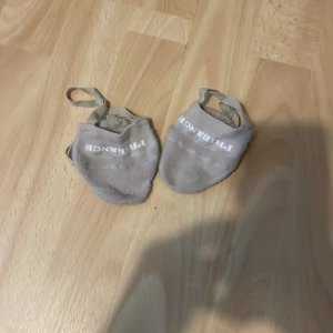 Beige dansskor/piruett skor  från Pridance - Säljer ett par beige typ av strumpor köpt vid Sm-shoppen 2024 i Västerås. Dessa användes delvis av dansare men även gymnaster när de är på en bom tex. Kan vara svårt att göra dina piruetter wolfturns osv barfota när du fastnar. Dessa e använda ett fåtal gånger då jag som sagt slutade 2024. De kan se rätt använda ut men undersidan är menad att ha en annan textur så du kan lättare få glid eller vad man ska säga. De finns ingen riktig storlek på den men jag har 36-37 i sko storlek o de passar bra