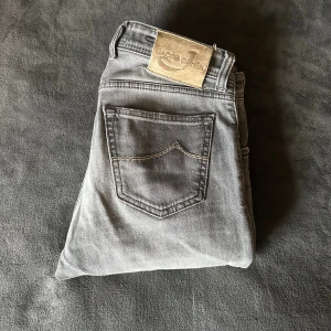 Grå jeans från Jacob Cohen - Grå Jacob Cohen-jeans i exklusiv denim med en avslappnad look. Skräddarsydd passform, handgjorda detaljer och karakteristisk elegans som kombinerar lyx med vardagsstil. Vid frågor och funderingar tveka inte på att höra av dig!