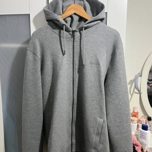 Hugo Boss zip up hoodie / luvtröja med dragkedja / kofta - Jätte fin Hugo boss zip up hoodie Storlek L Grå/mörk grå färg med broderad logga Precis som ny Skicka meddelande vid några funderingar Kolla gärna även in mina andra annonser
