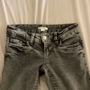 Grå bootcut jeans från Gina Tricot XS - Snygga grå jeans från Gina Tricot i bootcut-modell med utsvängda ben och klassisk femficksdesign. Jeansen har låg midja, silverfärgad knapp och slitningar som ger en cool tvättad look. 